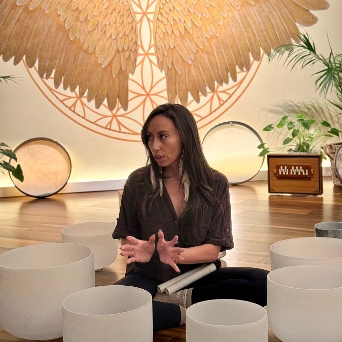 Bella Rivera demonstrating sound bath techniques during a sound healing training session in Sedona, Arizona, using singing bowls for vibrational healing.